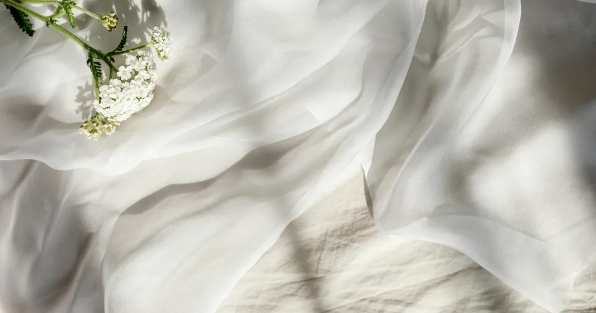 Soft white fabric adorned with delicate flowers, bathed in gentle sunlight.