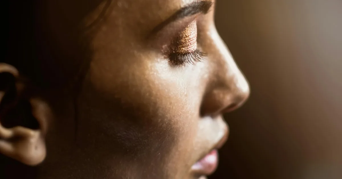 Artistic side profile of a woman's face highlighting skin texture and eye makeup.