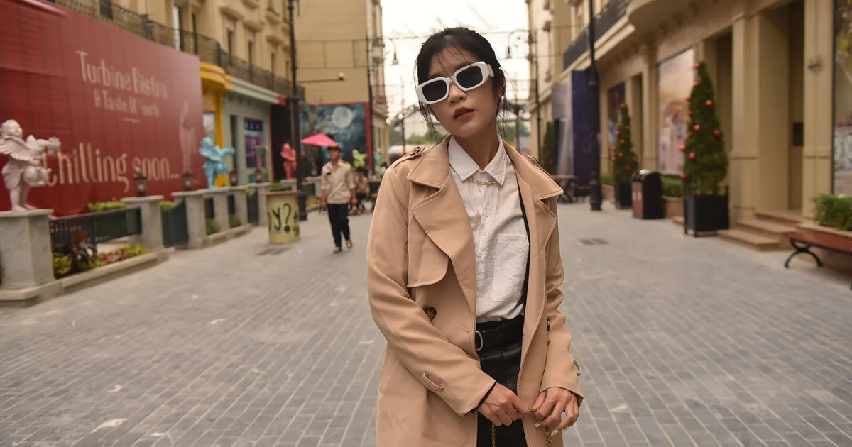Stylish woman with sunglasses posing confidently in a chic city street in spring.