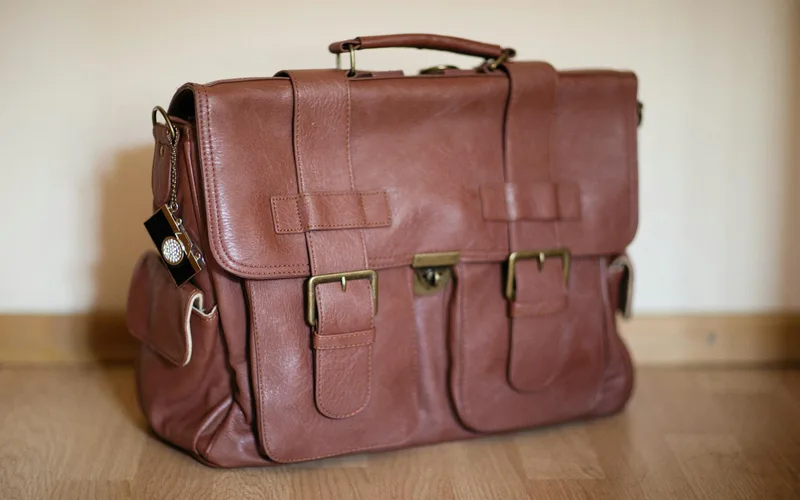 Stylish brown leather satchel on wooden flooring, perfect for travel or business.