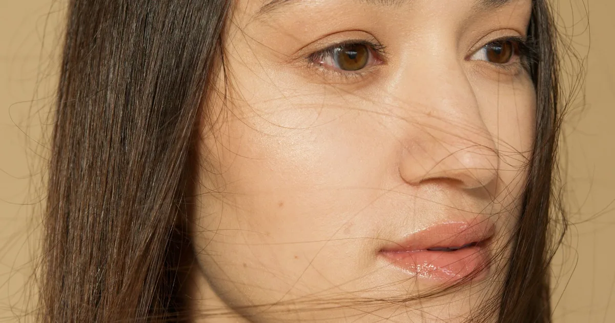 A serene close-up portrait of a woman with long, flowing hair and clear skin.