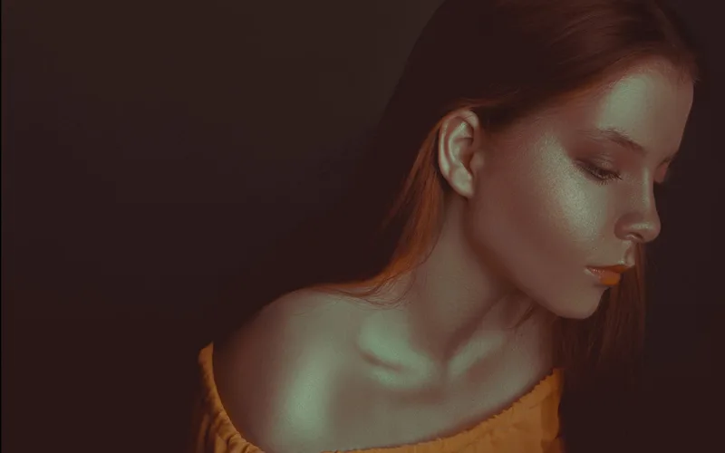 Stylish portrait of a woman with off-shoulder top in warm tones, showcasing beauty and serenity.