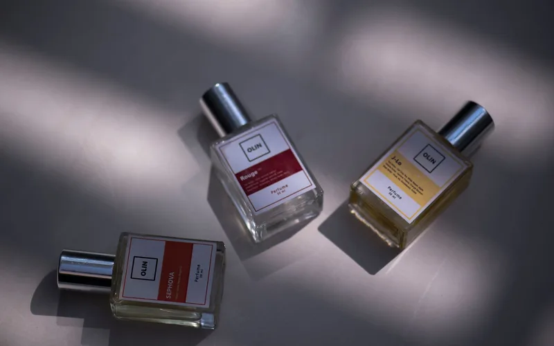 A still life shot of three elegant perfume bottles on a flat surface under soft lighting.