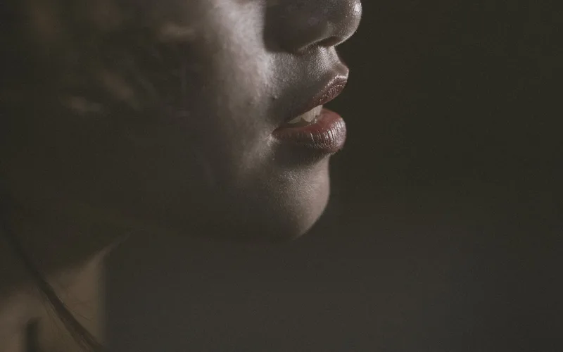 Artistic close-up portrait of a woman's face highlighting her lips in shadow.