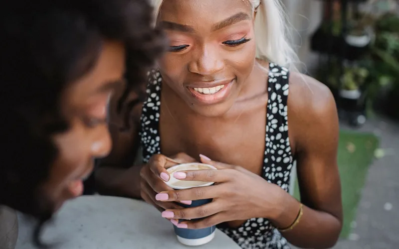 Two women enjoying a coffee and conversation outdoors, capturing a moment of leisure and friendship.