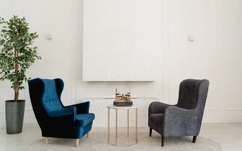 Stylish room setup with blue and grey armchairs, decorative plant, and table.