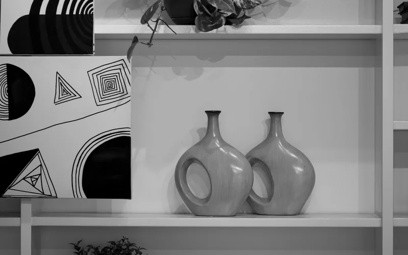 Elegant black and white decor featuring abstract art and stylish vases on a shelf.
