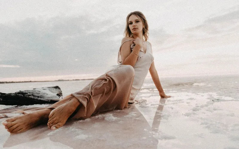 Serene portrait of a woman in a flowing dress on stunning salt flats during sunset.