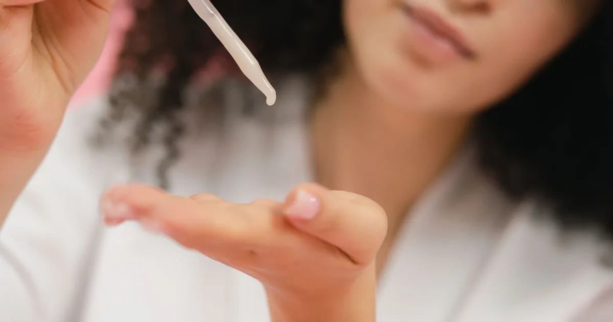Close-up of a woman applying skincare serum with a pipette, focusing on body care and cosmetic application.