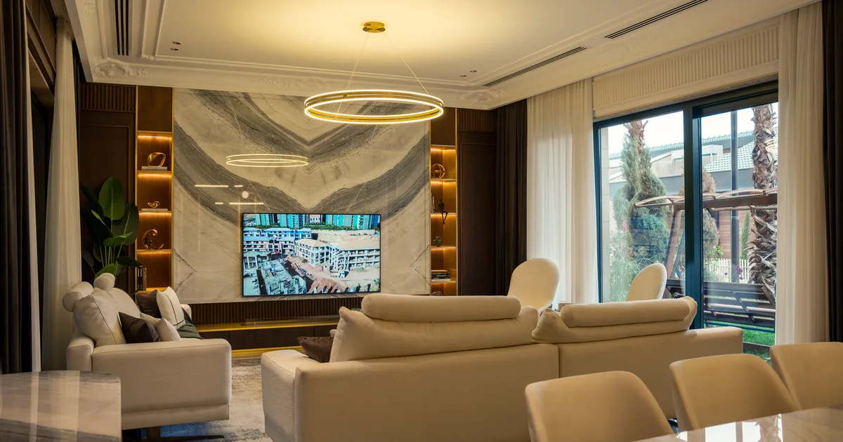 Elegant living room featuring modern furnishings, a large TV, and stylish lighting.