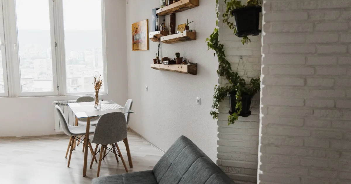 Bright and contemporary apartment interior with dining table, sofa, and decorative plants.